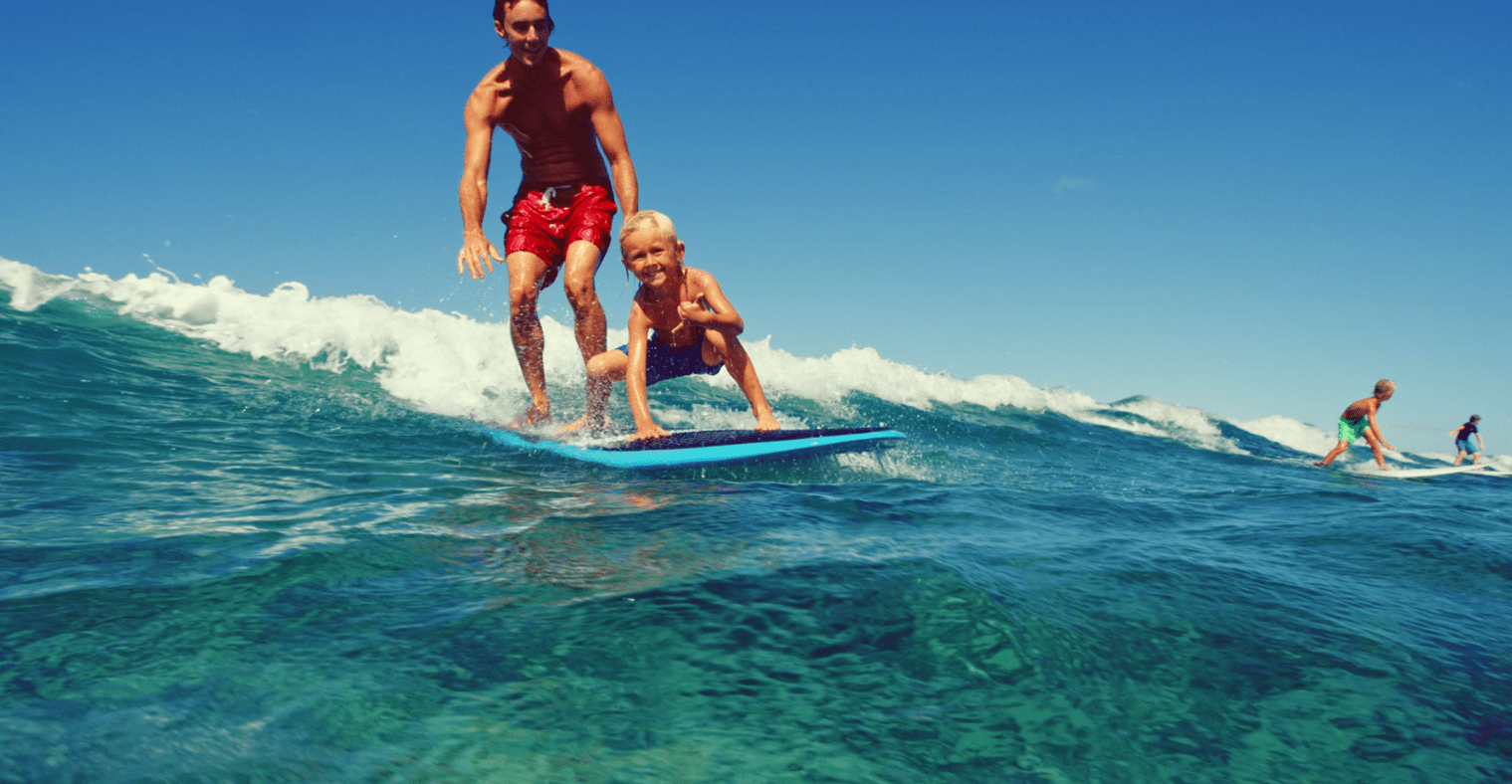 Man and boy surfing on a wave.