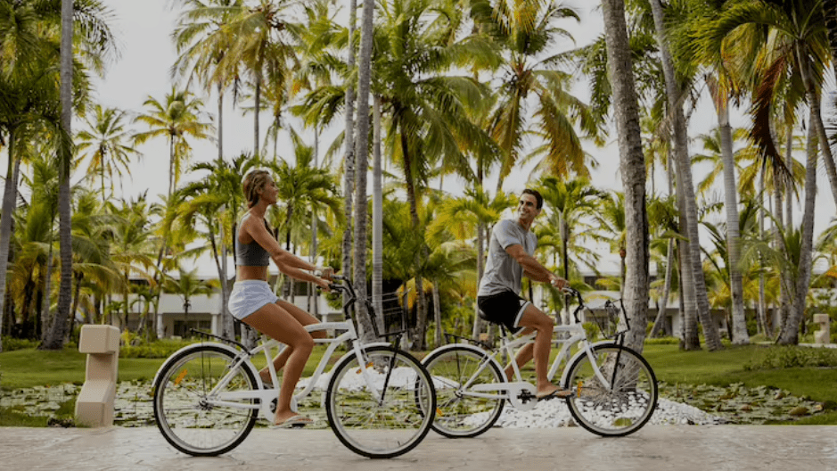 Couple bike riding through palm trees.