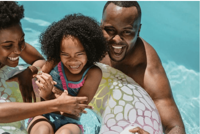 Family smiles in inflatable ring at pool.