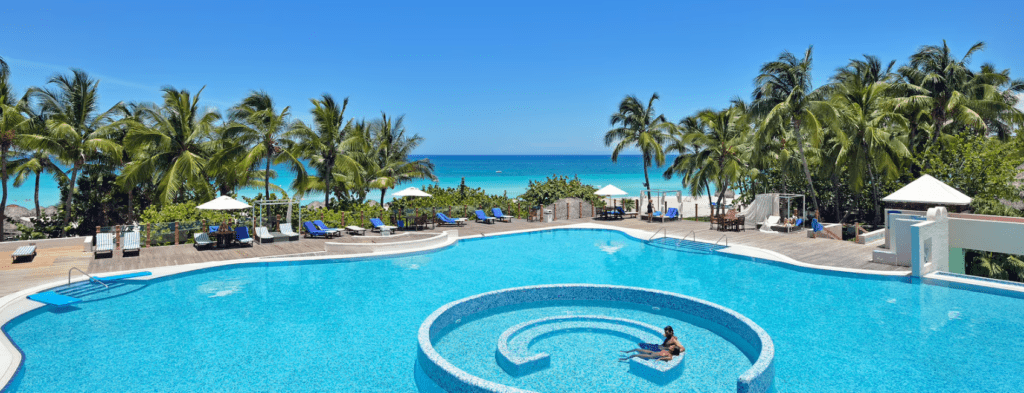 Couple swimming in resort pool by the beach.