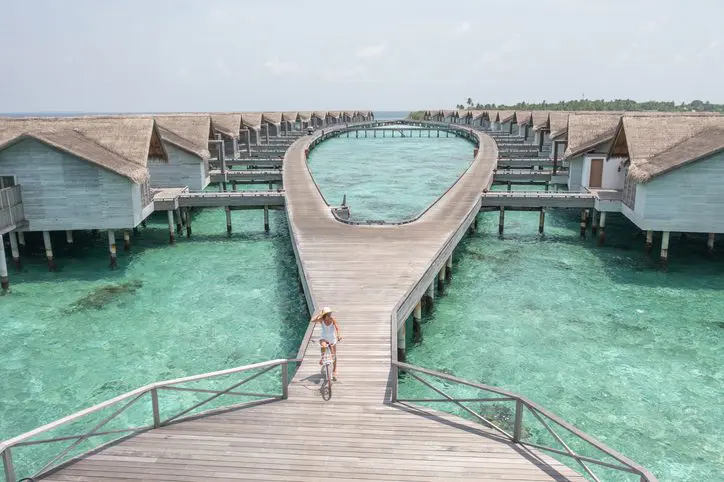 Woman cycling on wooden walkway over water.