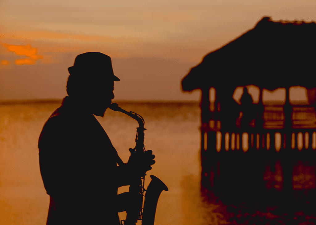 Silhouette of man playing saxophone at sunset.