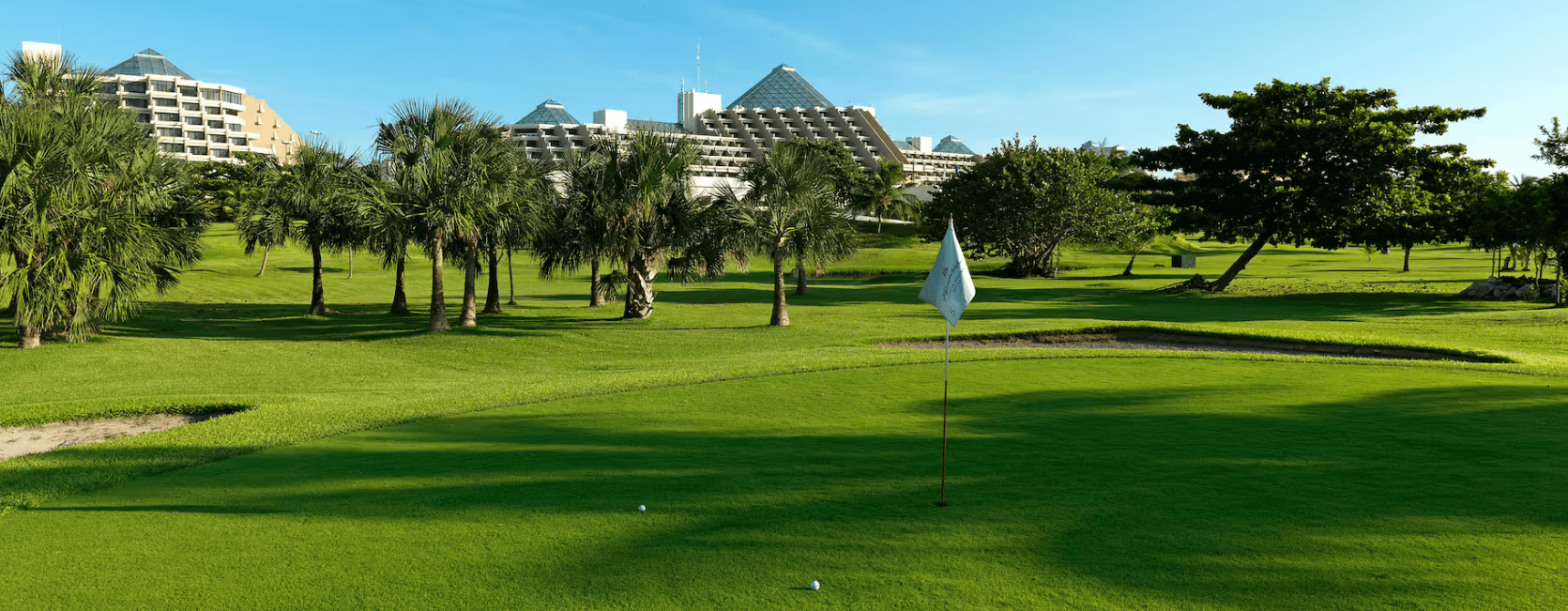 Golf course with palm trees and hotel.