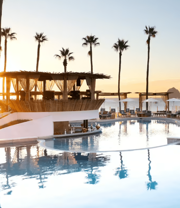 Poolside bar with palm trees and sunset.