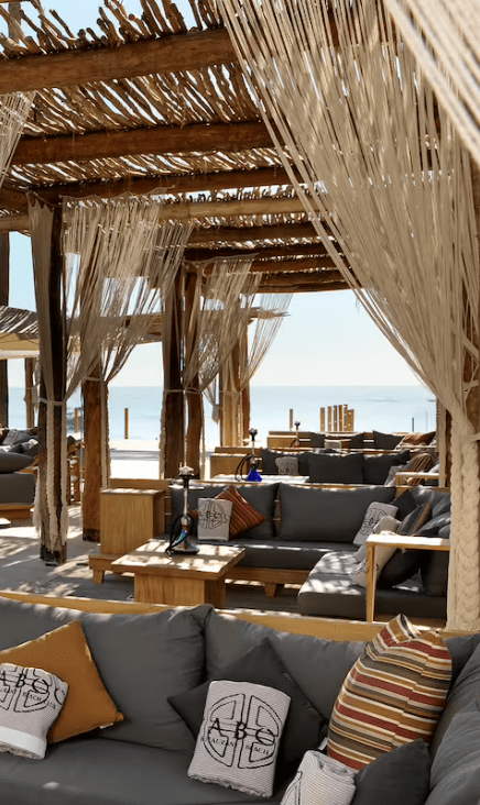 Beach lounge with wooden canopy and cushions.