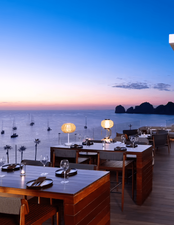 Outdoor dining with ocean view at sunset.