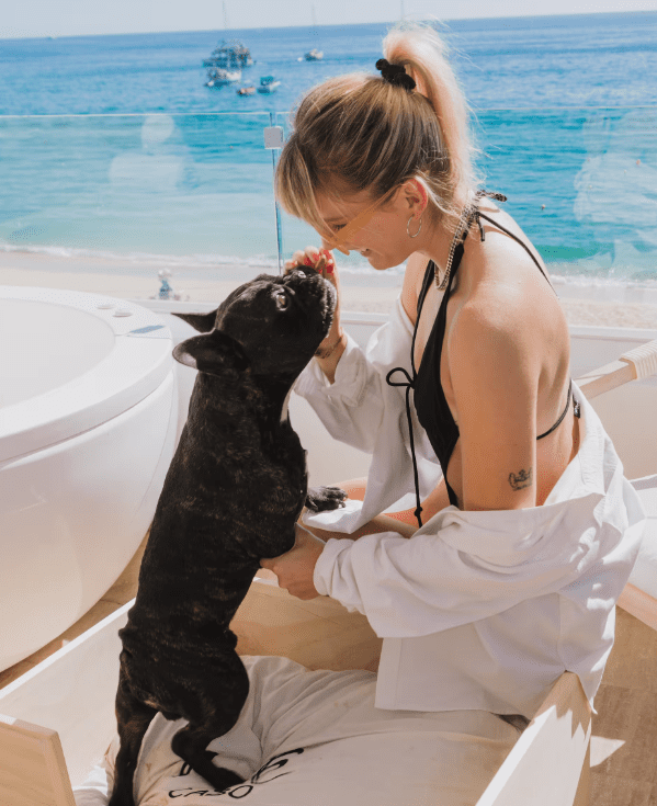 Woman in white shirt petting black dog.