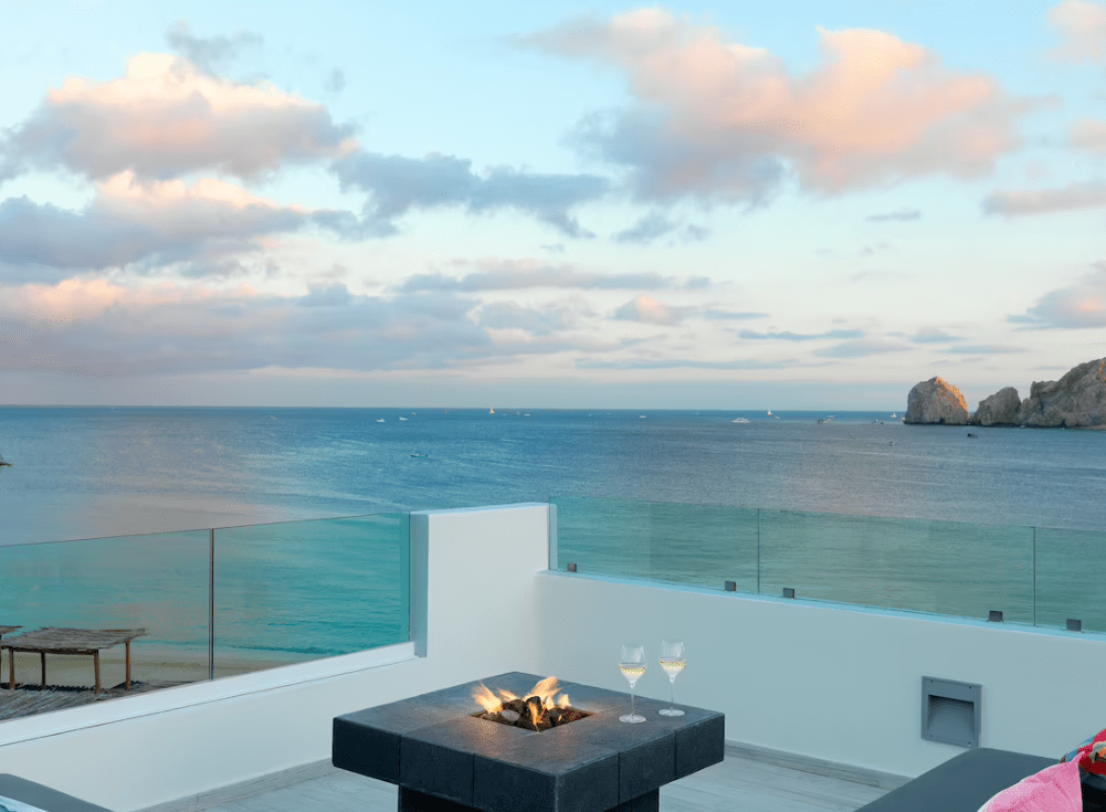 Ocean view patio with fire pit and wine glasses.