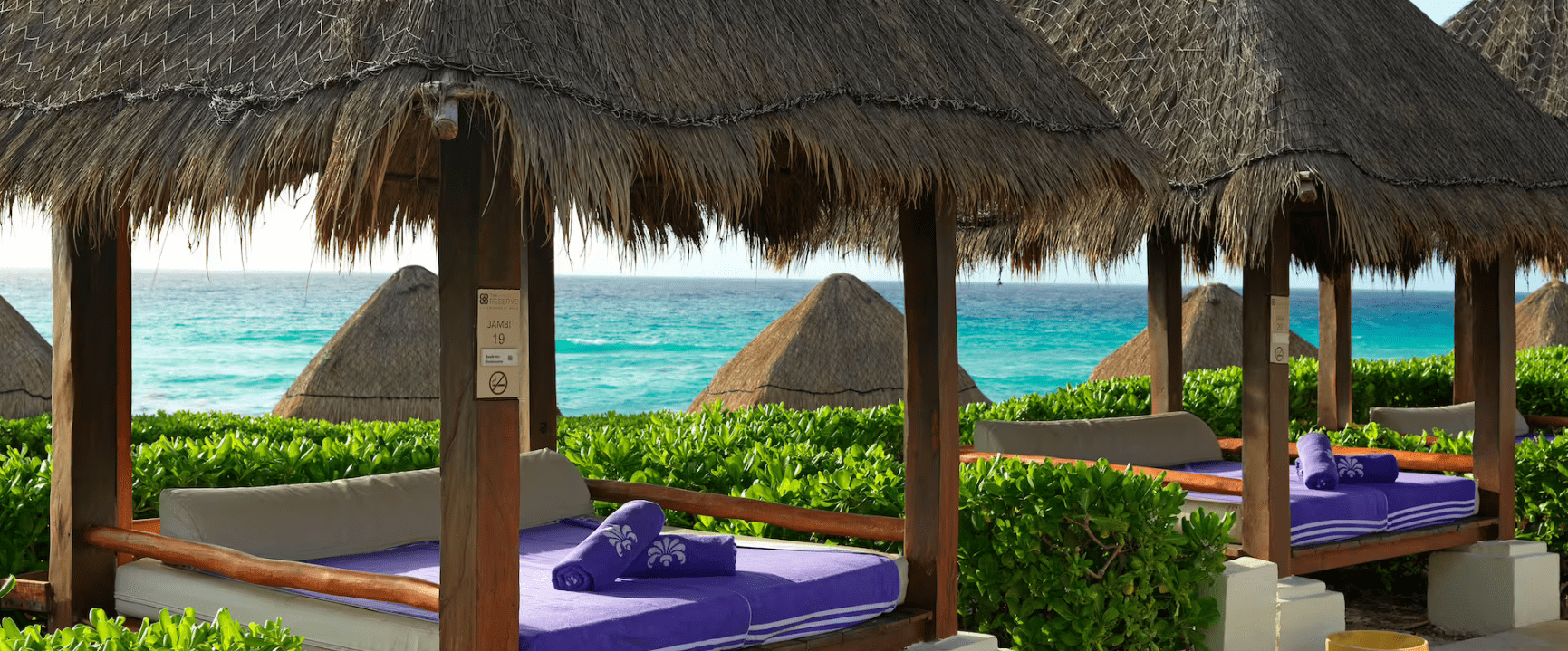 Beachfront cabana with purple towels.