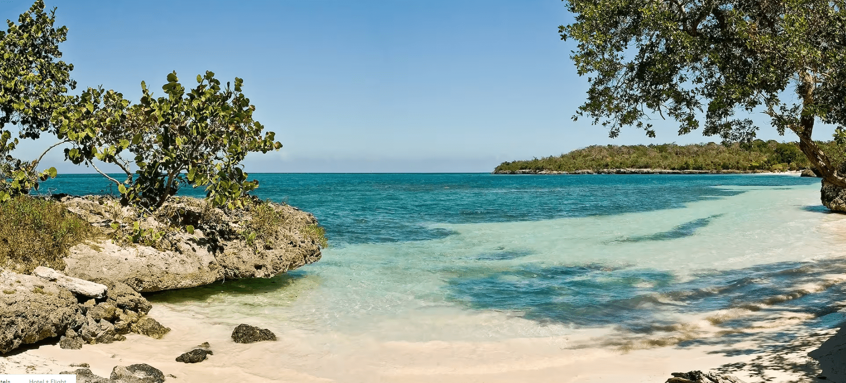 Tropical beach with turquoise water and rocks.