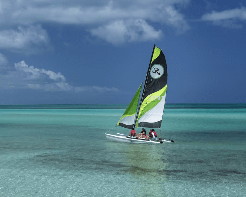 Sailboat with people on a clear blue ocean.