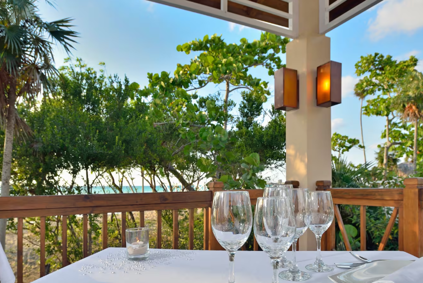 Outdoor dining with wine glasses and ocean view.