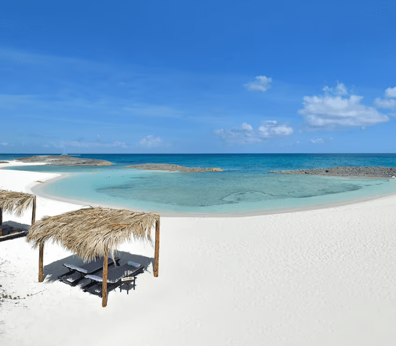 White sand beach with thatched cabanas.