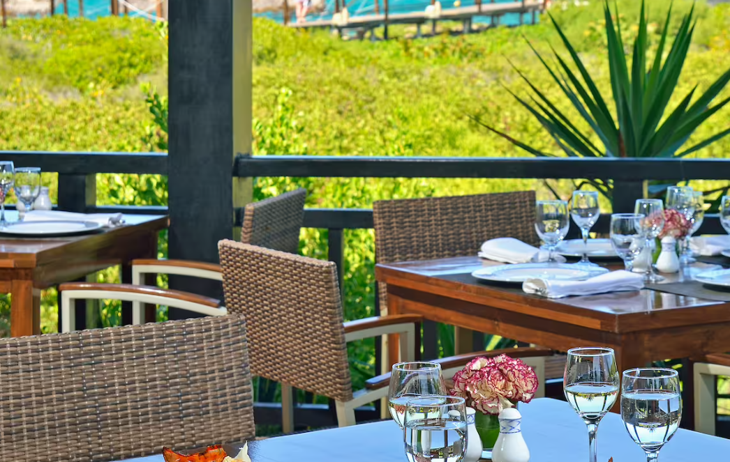 Outdoor dining table with wicker chairs and flowers.