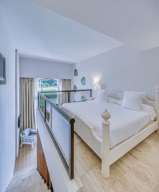 White bed in loft bedroom with railing.