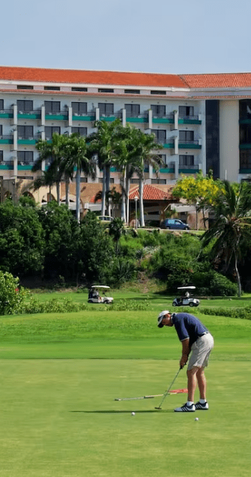 Golfer putting on green near resort.