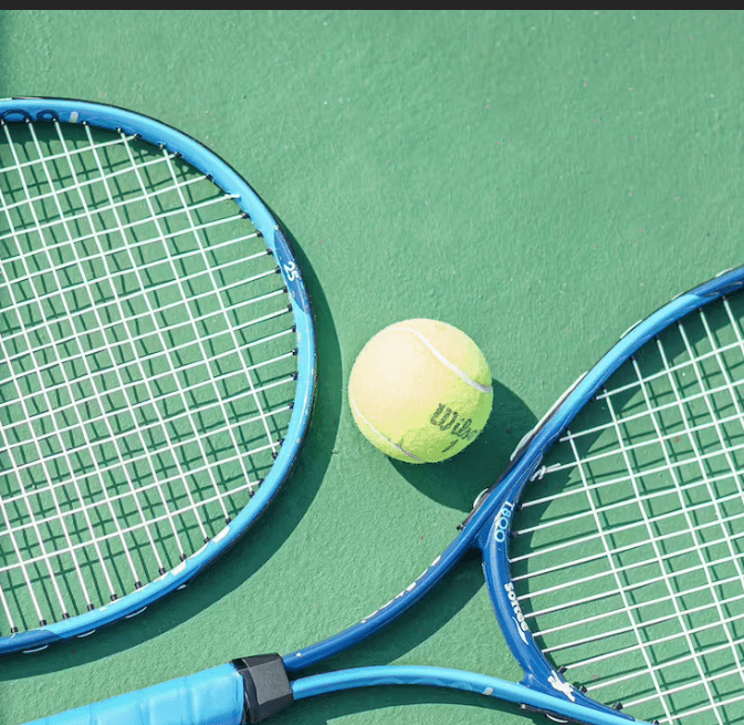 Two tennis rackets and a ball on court.