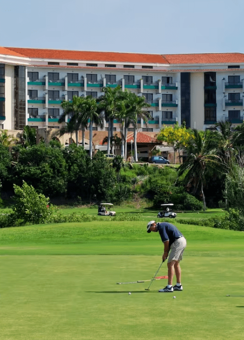 Golfer putting on green near resort.