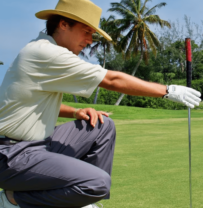 Golfer in hat holding putter on course.