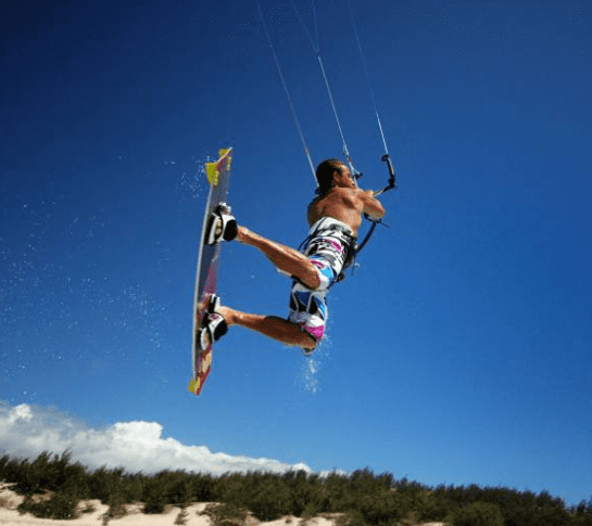 Man kitesurfing on a blue sky day.