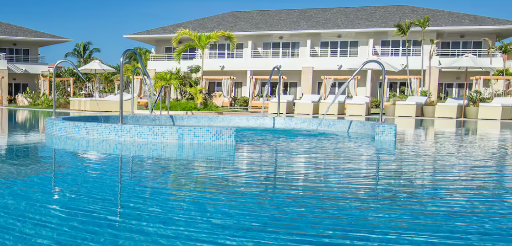 Swimming pool with tiled edge in front of resort.