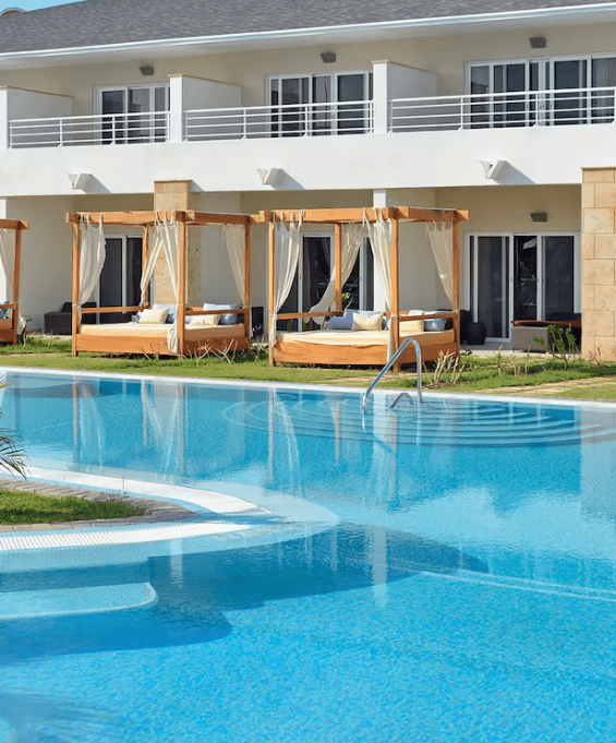 Swimming pool with cabanas and a resort building.