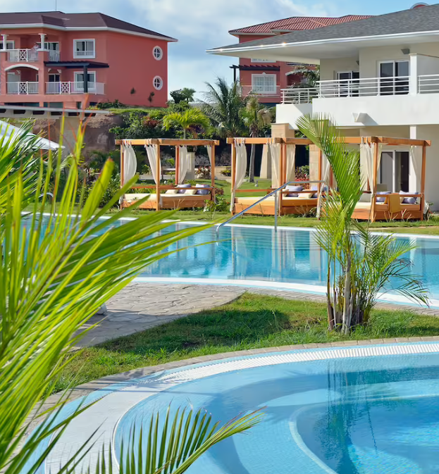 Resort pool with cabanas and palm trees.