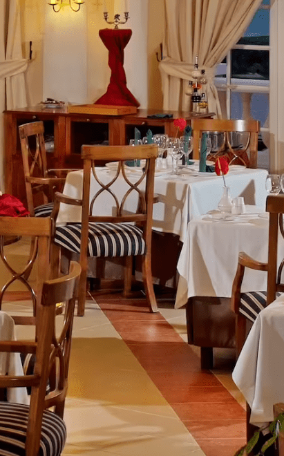 Formal dining room with wooden chairs and white tablecloths.