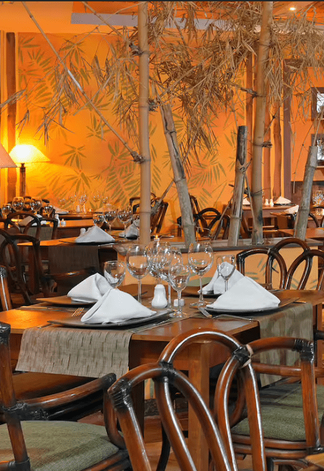 Restaurant tables and chairs with bamboo decor.