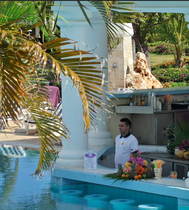 Palm tree by poolside bar with bartender.