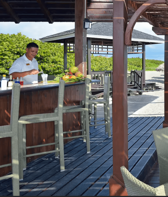 Beach bar with a bartender and stools.