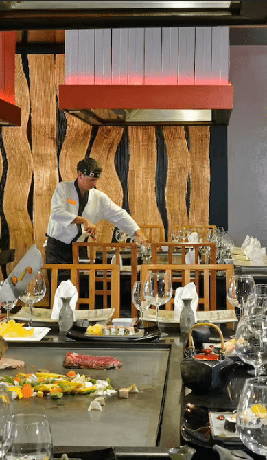 Chef preparing food at a teppanyaki restaurant.