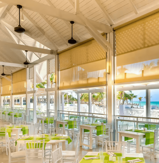 Beachfront restaurant with white tables and chairs.