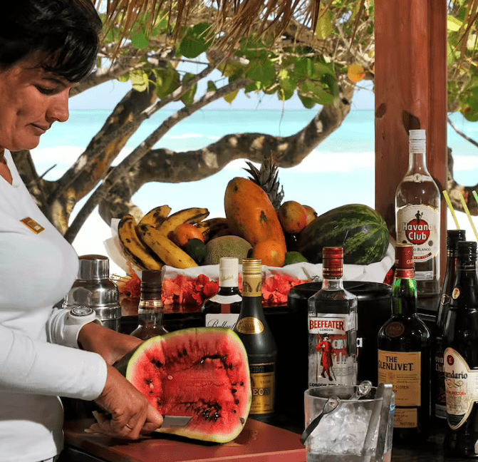 Woman cutting watermelon at tropical bar.