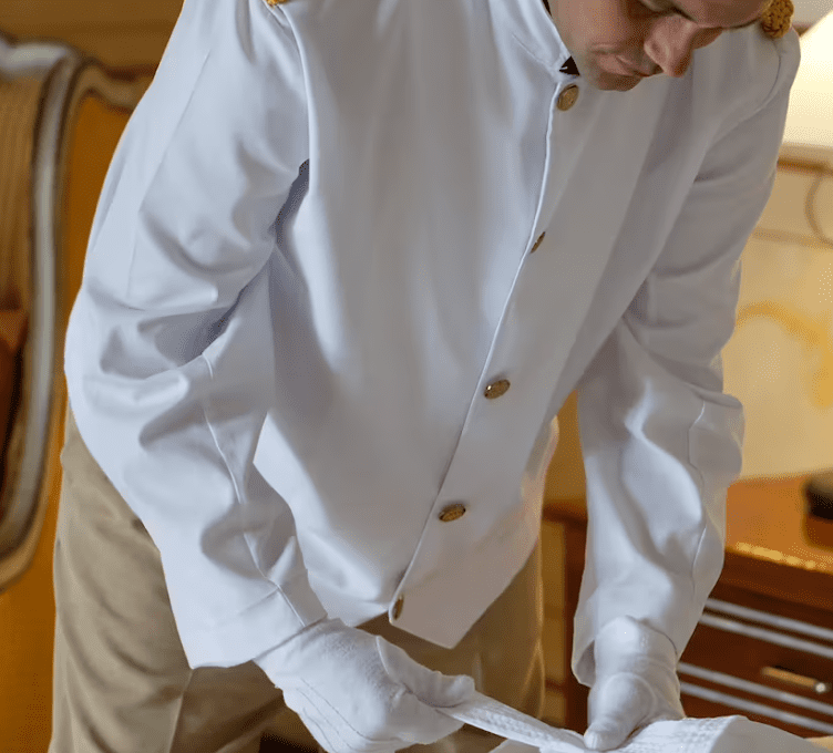 Man in white uniform making bed.