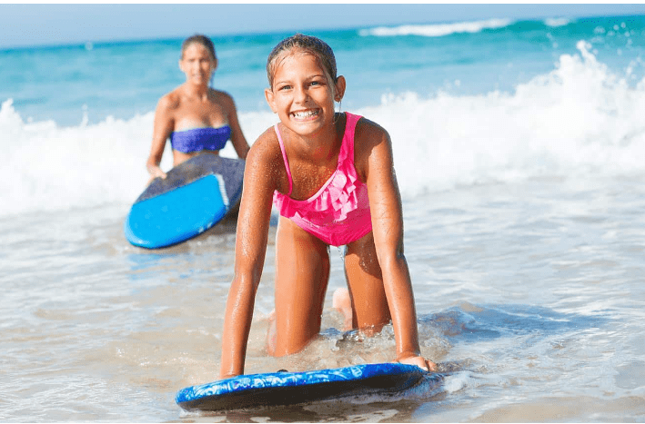 Smiling girl on surfboard in ocean.