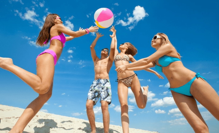 Four friends playing beach volleyball.