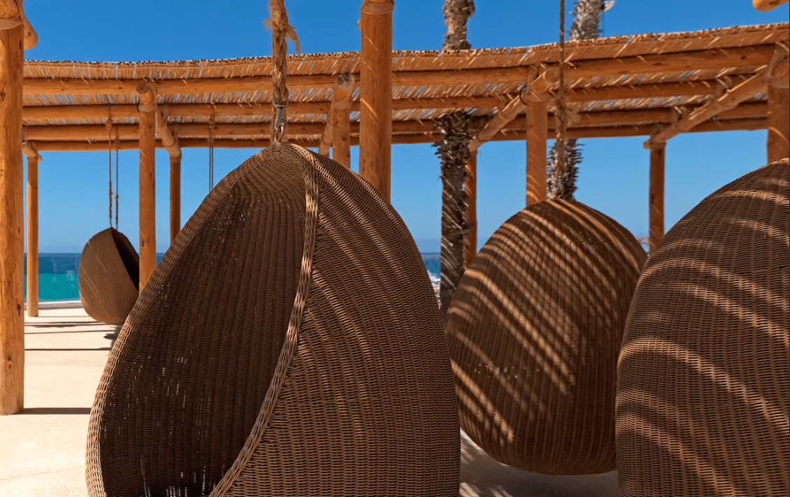 Wicker hanging chairs under a pergola.