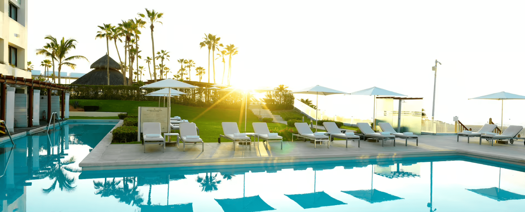 A resort pool with lounge chairs and palm trees.