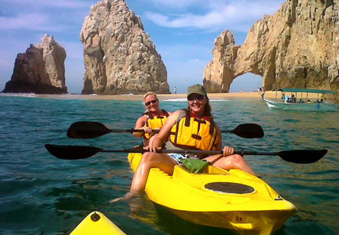 Two women kayaking near rock formations.