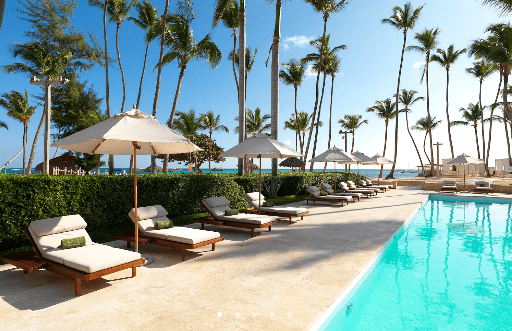 Palm trees, pool, loungers, and a resort.