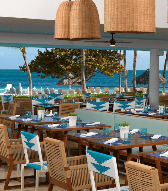 Oceanfront restaurant with wicker chairs and blue accents.