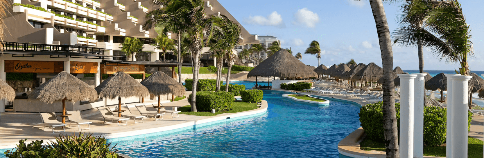 Resort pool with palm trees and ocean view.