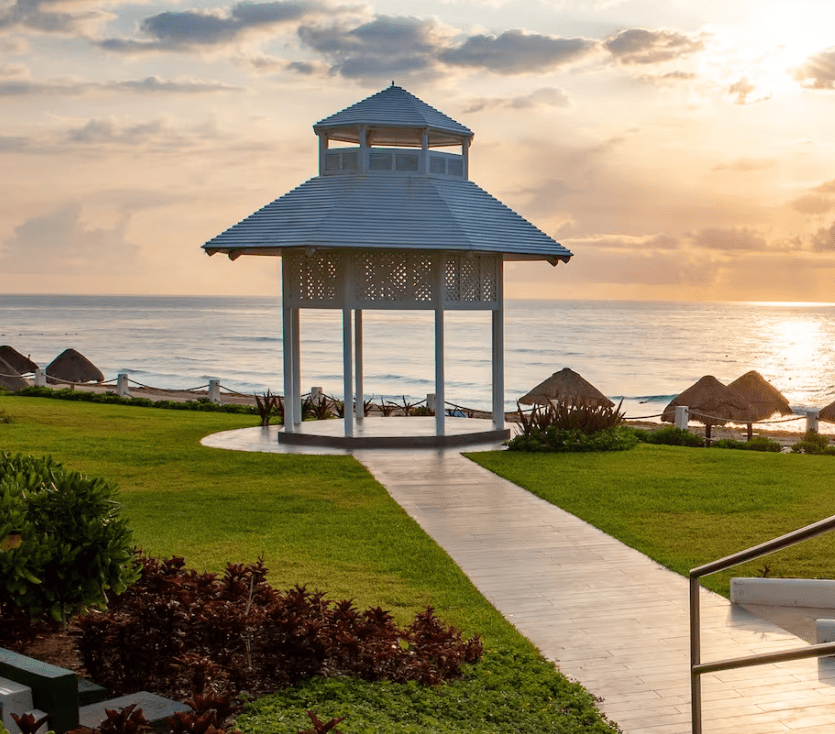 White gazebo on beach at sunrise.