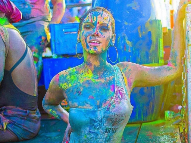 A woman is covered in colorful paint at a festival.