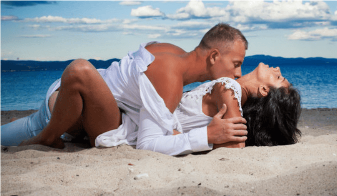 Couple embracing on a sandy beach.