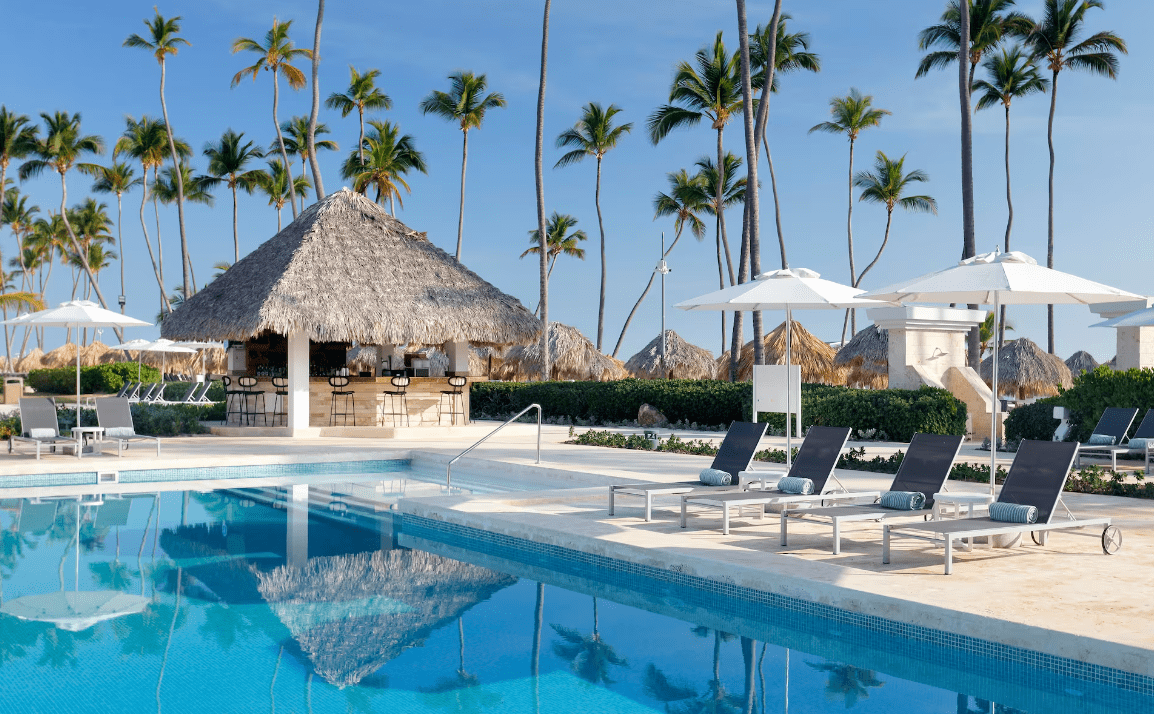 Poolside bar with lounge chairs and palm trees.