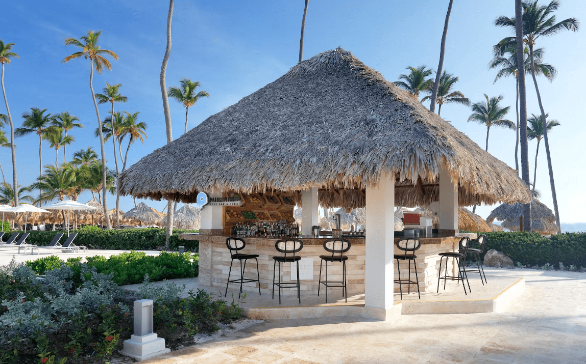 Beach bar with thatched roof and stools.