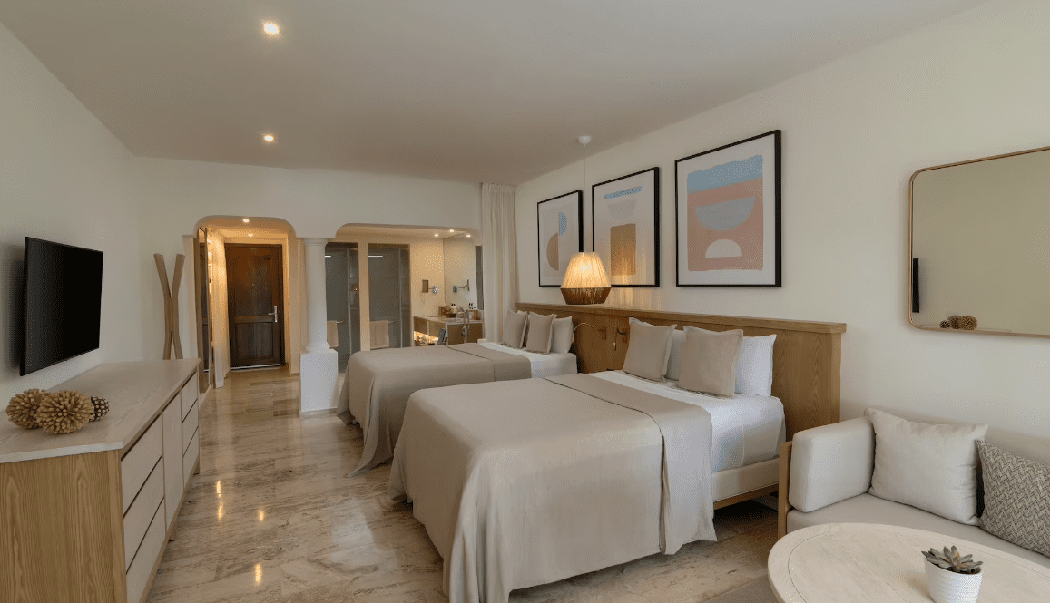 Hotel room with two beds, TV, and sitting area.