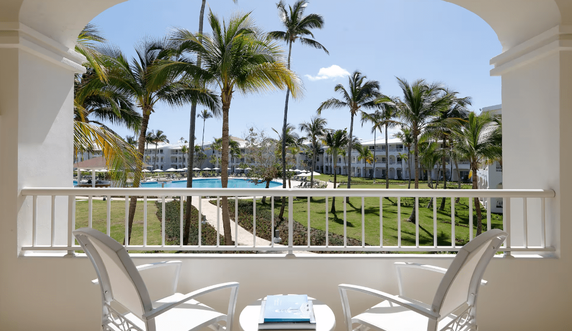 Two chairs on a balcony overlooking a tropical resort.